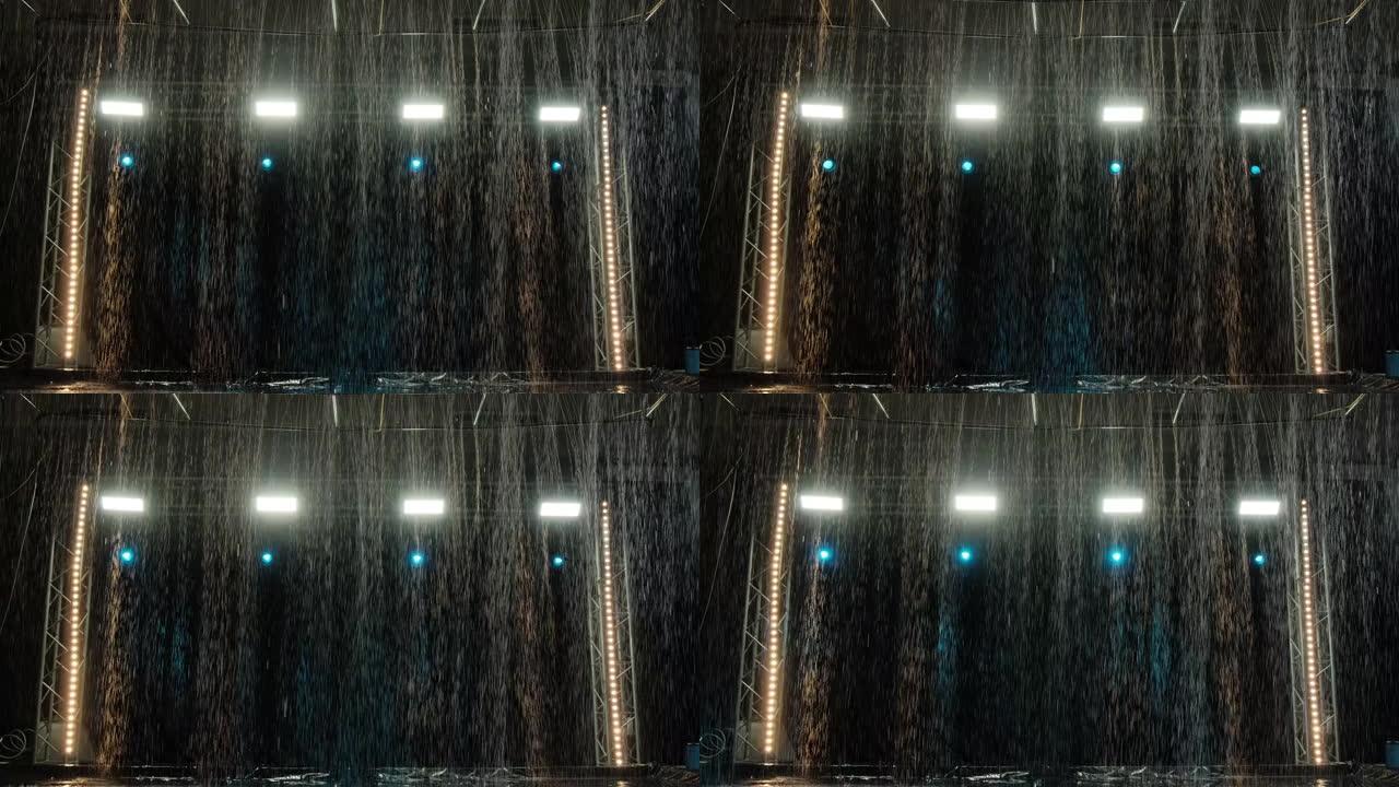 在聚光灯的背景下，水上工作室里下雨的效果。水质地。慢动作