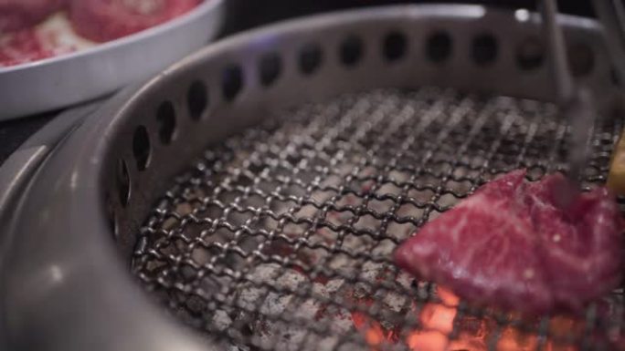 4k日式手拿牛肉片放在烧烤架上，做得很好，中等稀有肉，煤火，日本餐厅，午餐，火焰烤，白盘，餐厅主菜