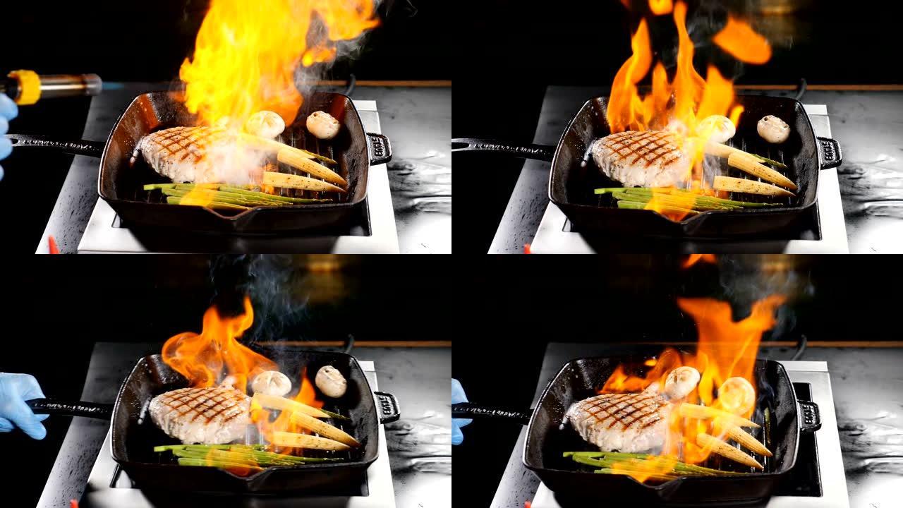 专业厨师在餐厅厨房烹饪flamb é 风格的菜肴。用火焰盘点燃和搅拌煎锅。高级美食。慢动作。高清