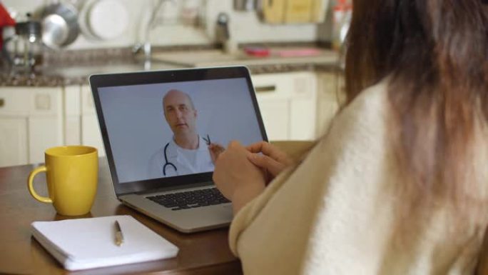 生病的女人在家里的笔记本电脑屏幕上进行视频通话时咨询医生。医生在远程会诊时解释诊断。远程医疗，而自我