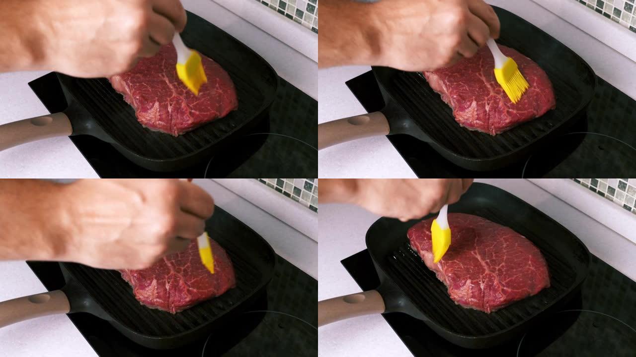 男人用硅胶刷在烤盘上的烤牛排上用手抹油