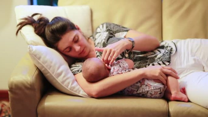 坦率的休闲母亲和婴儿一起坐在家里的沙发上