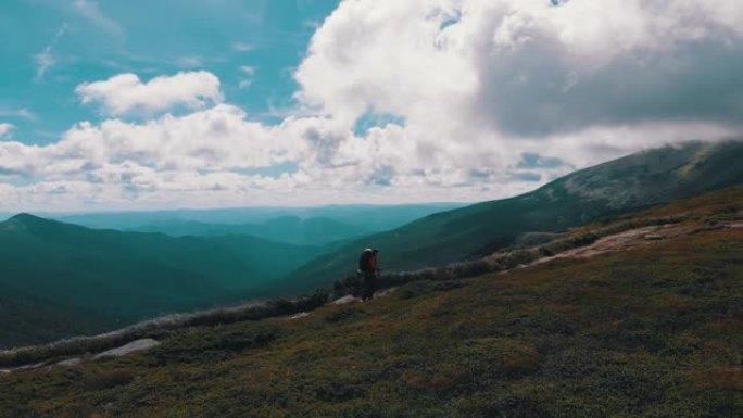 背着背包沿着山坡攀爬的旅行者的鸟瞰图。史诗般的镜头