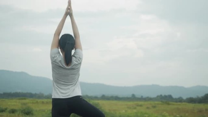 年轻的亚洲妇女做瑜伽练习冥想，在日出时在山景中表演精神瑜伽姿势。