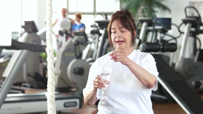 老年妇女在健身训练后喝水。
