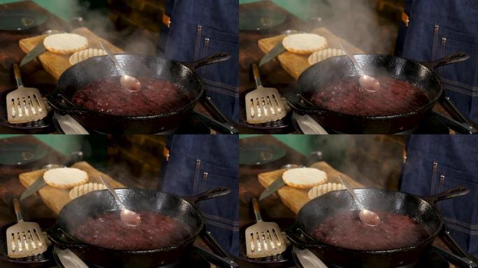 野生有机蔓越莓酱在铁锅中加热，白色蒸汽上升，烹饪概念。库存镜头。汉堡甜酱的制作过程