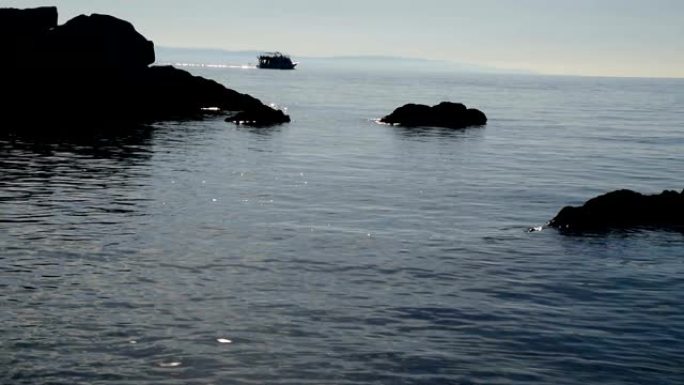 背景中从海海和船只升起的岩石剪影