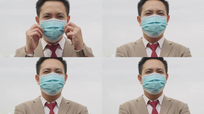 中型手持镜头: 亚洲商人戴着医用防护口罩的肖像，防止冠状病毒或新型冠状病毒肺炎，并在白色背景上看着相