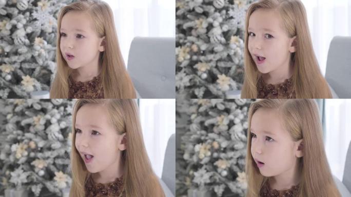 相机在可爱的长发白人女孩的脸上移动。除夕坐在圣诞树旁边的漂亮孩子。美丽，假期。