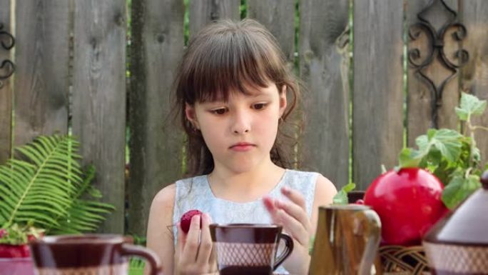 女孩坐在餐桌旁吃乡村浆果，舔手指