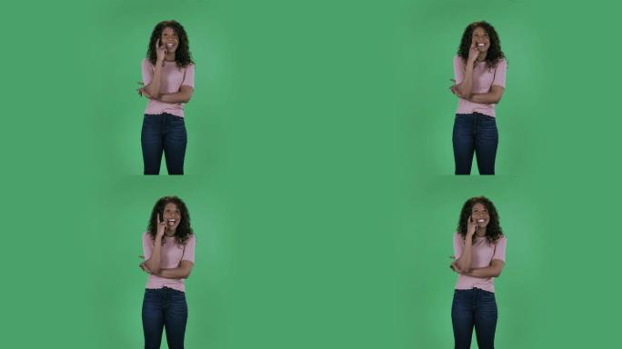 美丽的非洲裔美国年轻女子的肖像正在做白日梦，微笑着抬头。在工作室的绿色屏幕上燃烧着黑发，波浪状的牛仔