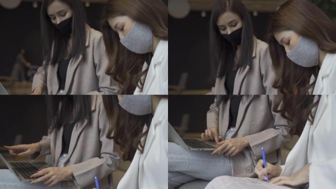 混合种族夫妇商务女性在办公室工作时使用笔记本电脑戴口罩