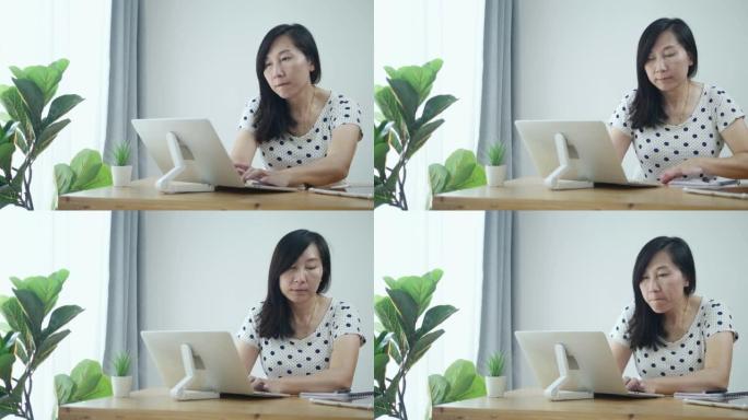 亚洲妇女使用笔记本电脑在新型冠状病毒肺炎期间在家工作。