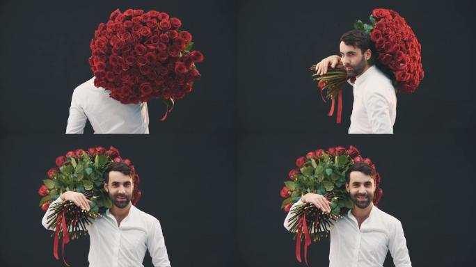 英俊的男人肩膀上有一大束玫瑰花站在镜头前，转过身，微笑着，扬起眉毛，看上去很诱人。