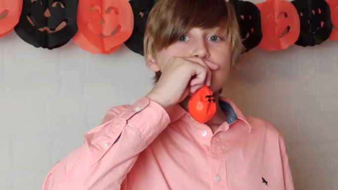 一个金发男孩喜欢挥舞着杰克o灯笼的橙色南瓜气球，膨胀气球