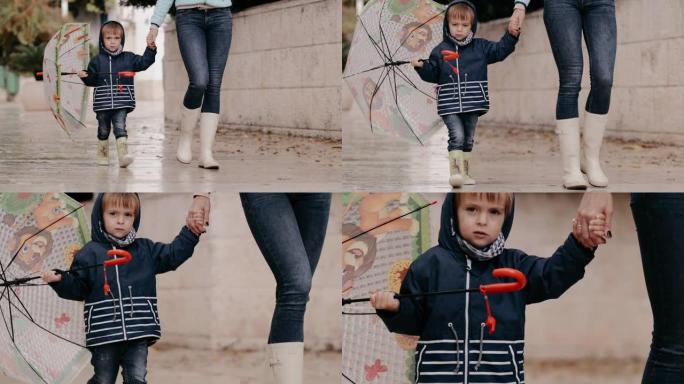 妈妈和儿子穿着橡胶靴和雨伞在雨中行走。