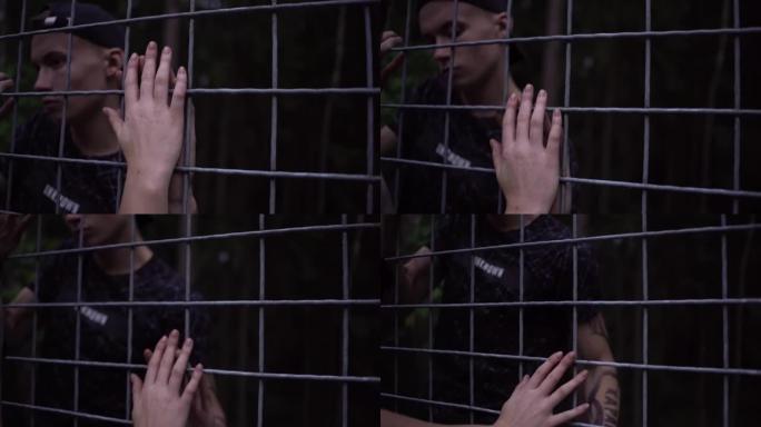 男孩和女孩用手指通过铁笼互相触摸。