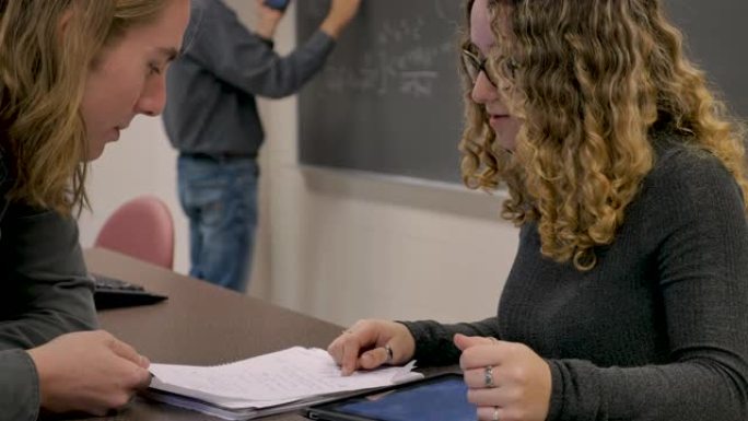 两名大学生在教室里一起看着数字平板电脑