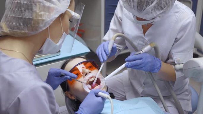 牙医在牙科诊所进行手术，患者在全身麻醉下躺在桌子上
