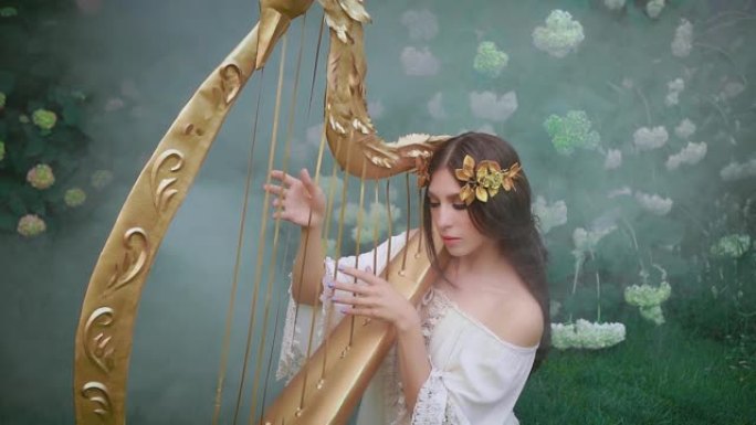 温柔的女孩可爱的天使般的脸在竖琴上演奏精灵歌曲旋律。希腊女神