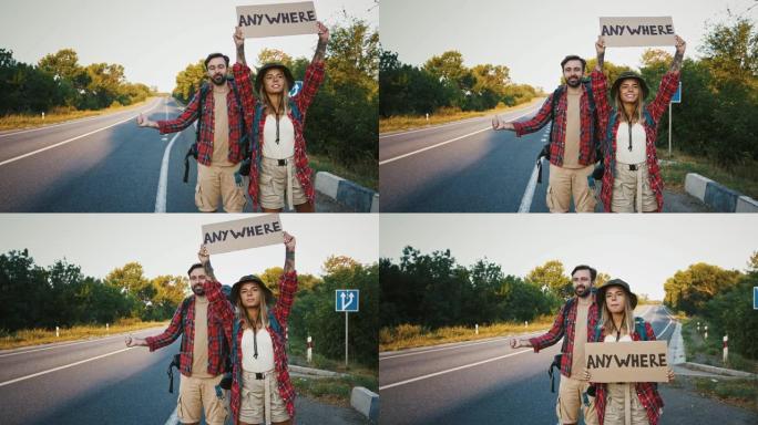 年轻夫妇试图在道路上赶上汽车，在任何地方举着标志