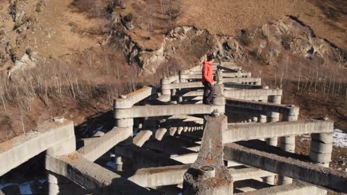 白天坐在山区高泥流保护结构顶部的男性极端鲁夫的鸟瞰图。泥石流保护的概念以及休闲和屋顶的极端类型