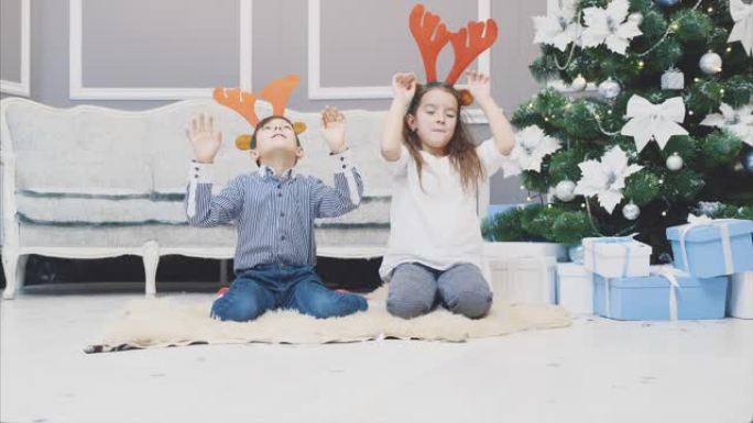 有趣的视频，兄弟姐妹戴着圣诞节驯鹿鹿角，在他们面前鞠躬，微笑着，看起来很可笑。