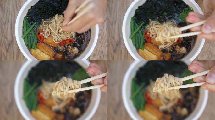 健康的有机亚洲美食。筷子从热鲜辣拉面汤中挑面的顶级镜头