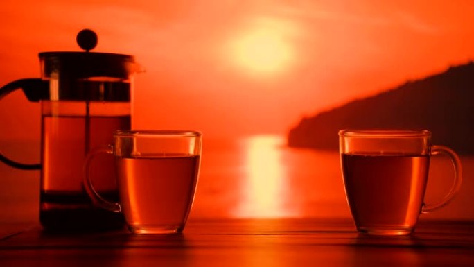 日落时分，两杯热茶放在海边的桌子上