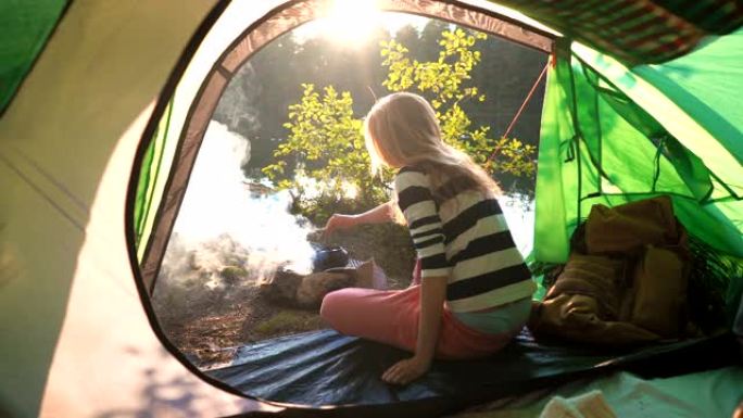 一个年轻女子在森林湖岸的帐篷里