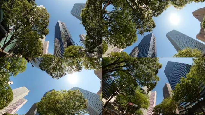 开车穿过城市的摩天大楼。扭转并仰望摩天大楼和绿树的景色。