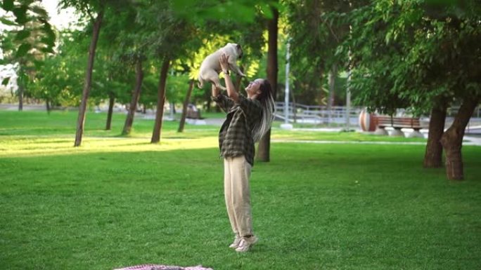 女孩和哈巴狗玩得很开心，她把狗扔到公园的空中