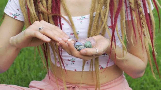 女孩长发锁发型手握小天然石头玫瑰夸兹，水钻，天使石，anyolite和azurite，脸不可见