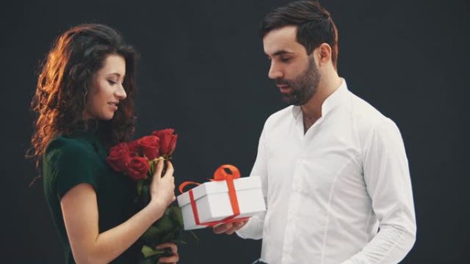 快递员给可爱的古怪女孩送一束红玫瑰和盒子。她放了一个签名，闻到了花的味道，看起来完全惊讶。