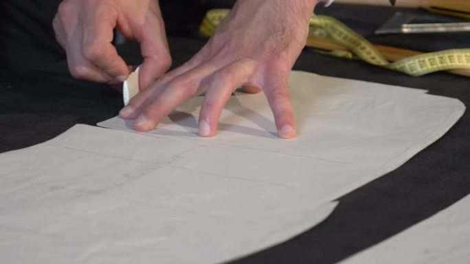 裁缝在将织物切成零件以进行进一步加工之前在织物上绘制最终线条的镜头