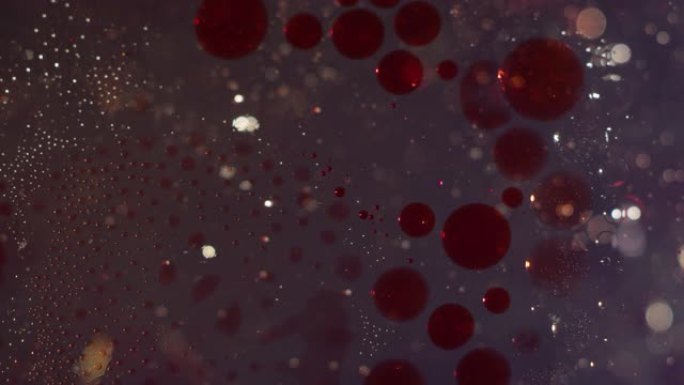 红色和透明气泡在液体bokeh背景上融合在一起