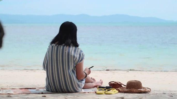 亚洲妇女在暑假时间坐在海滩上写明年的新年决议