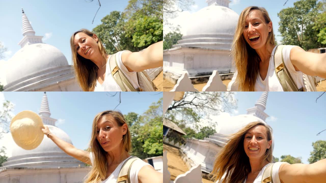 一名年轻女子在斯里兰卡旅游时拍摄自拍视频，并参观佛教的白色圆顶佛塔古寺。女孩旅行拍摄冒险与自拍