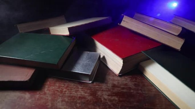 一堆旧书。木制桌子上的老式书籍。黑暗房间里发光的书周围有神奇的闪电。选择性聚焦
