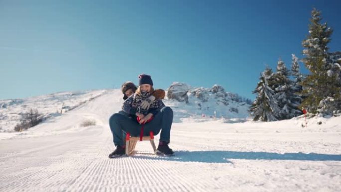 微笑的年轻夫妇一起坐在雪山上