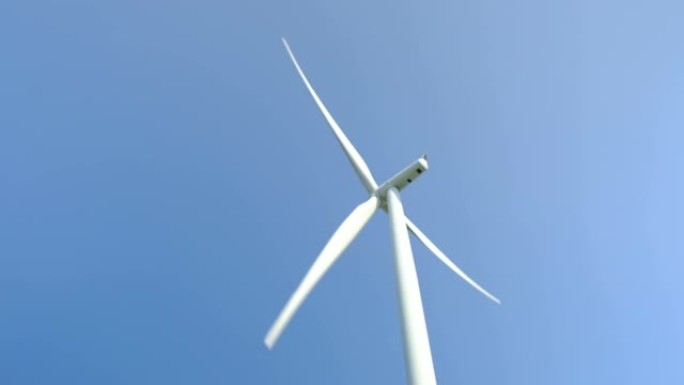 在风电场中关闭以蓝天背景旋转的风力涡轮机叶片。替代能源。