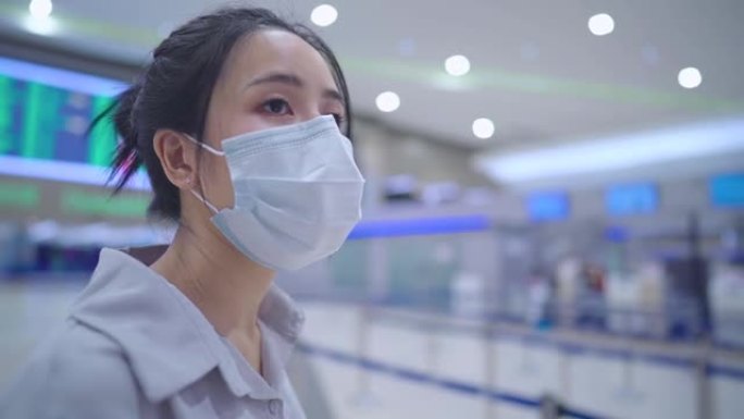 近距离观察亚洲年轻女子戴着防护口罩向朋友挥手、机场接机、机场航站楼到达大厅、新常态、探亲团聚