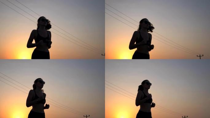 活跃的苗条女孩在乡村道路上慢跑，背景是夜空。从事跑步训练的女运动员。日落时分，年轻的运动女子在户外锻