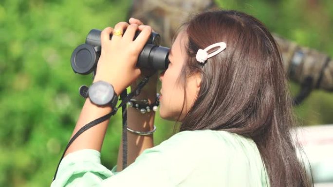 亚洲妇女在森林中使用双筒望远镜的场景，妇女旅行和使用双筒望远镜在森林中寻找鸟类，人们的生活方式户外活