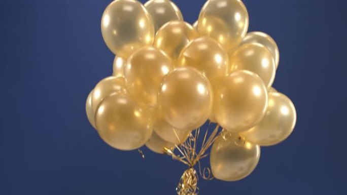 视频中出现了一个装饰元素-金色气球，作为蓝色背景的情人节，生日，圣诞节或新年的惊喜。