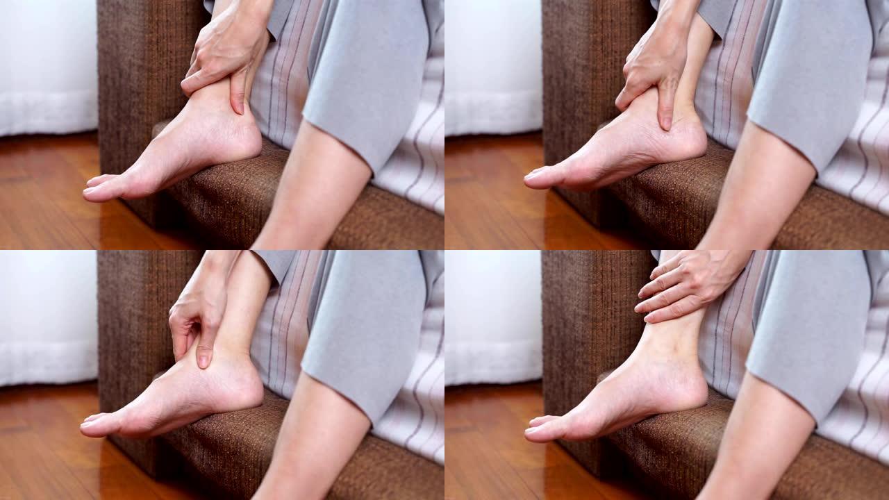 患有关节炎的年轻女性坐在床上，摩擦脚踝和脚缓解疼痛。怀孕脚痛概念。