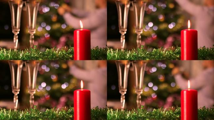 背景上有圣诞树装饰的圣诞蜡烛和香槟杯