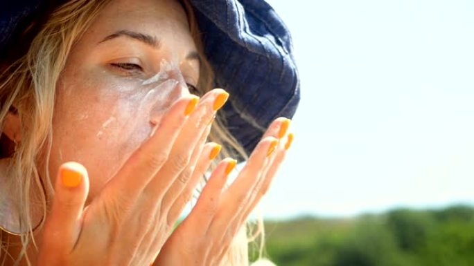 年轻女子在脸上涂防晒霜以防晒。慢动作。高清