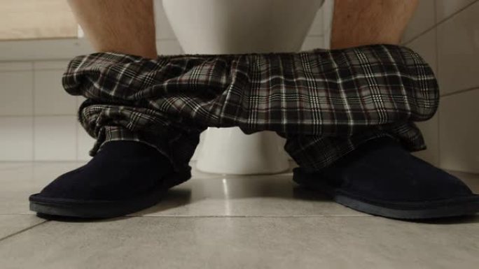 穿着睡衣和拖鞋的男性腿在厕所附近-他脱下衣服