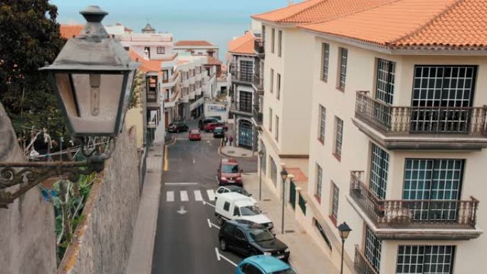 狭窄的欧洲街道，汽车驶向海边。前景是一盏路灯。可以用来说明西班牙、葡萄牙